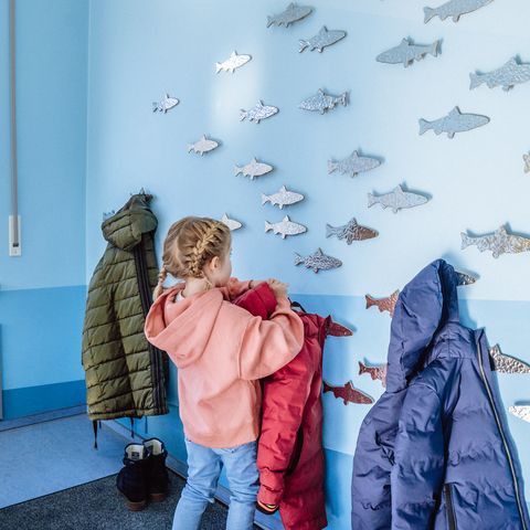 Ein Kind hängt seine Jacke an der Garderobe in Murgels Spielhaus auf.