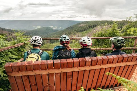 Vier Biker sitzen auf einer Bank am Huzenbacher Seeblick