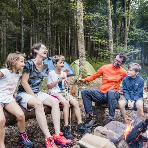 Eine Familie sitzt am Lagerfeuer im Trekking-Camp bei Baiersbronn.