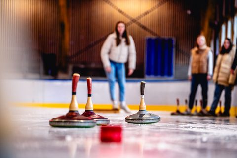 Eine Gruppe spielt Eisstockschießen in der Eislaufhalle in Baiersbronn