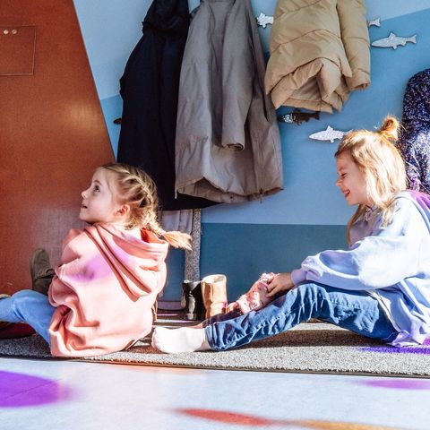 Kinder sitzen vor der Garderobe im Eingangsbereich von Murgels Spielhaus in Baiersbronn.