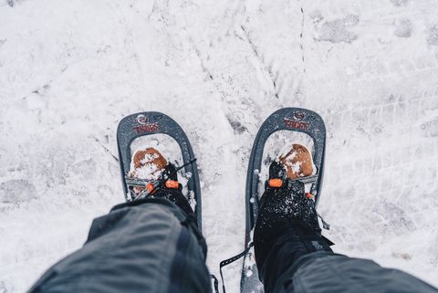 Eine Person steht mit angezogenen Schneeschuhen im Schnee.