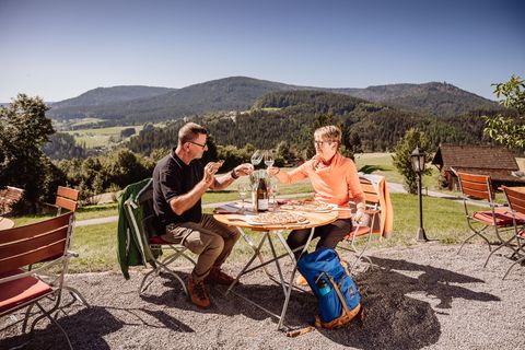 Ein Paar sitzt auf der Terrasse von Sackmanns Panoramahütte