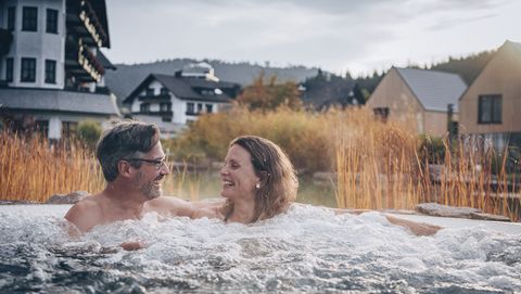 Ein Paar sitzt draußen im Whirlpool des Hotel Engel Obertal.